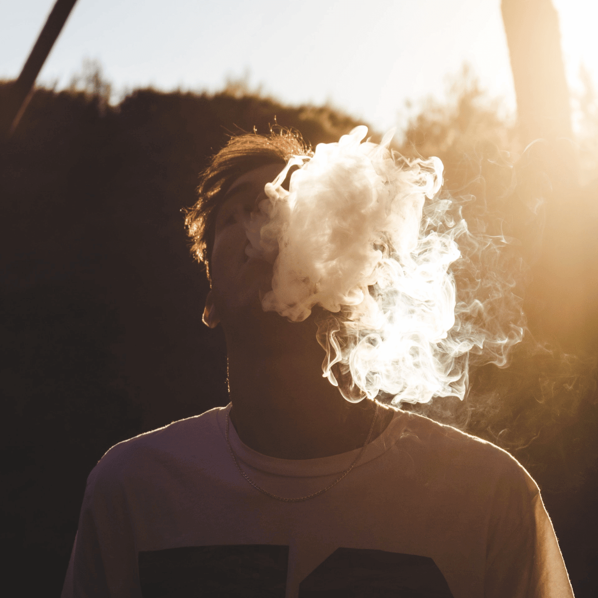Young men exhaling smoke from a joint in the sun light 